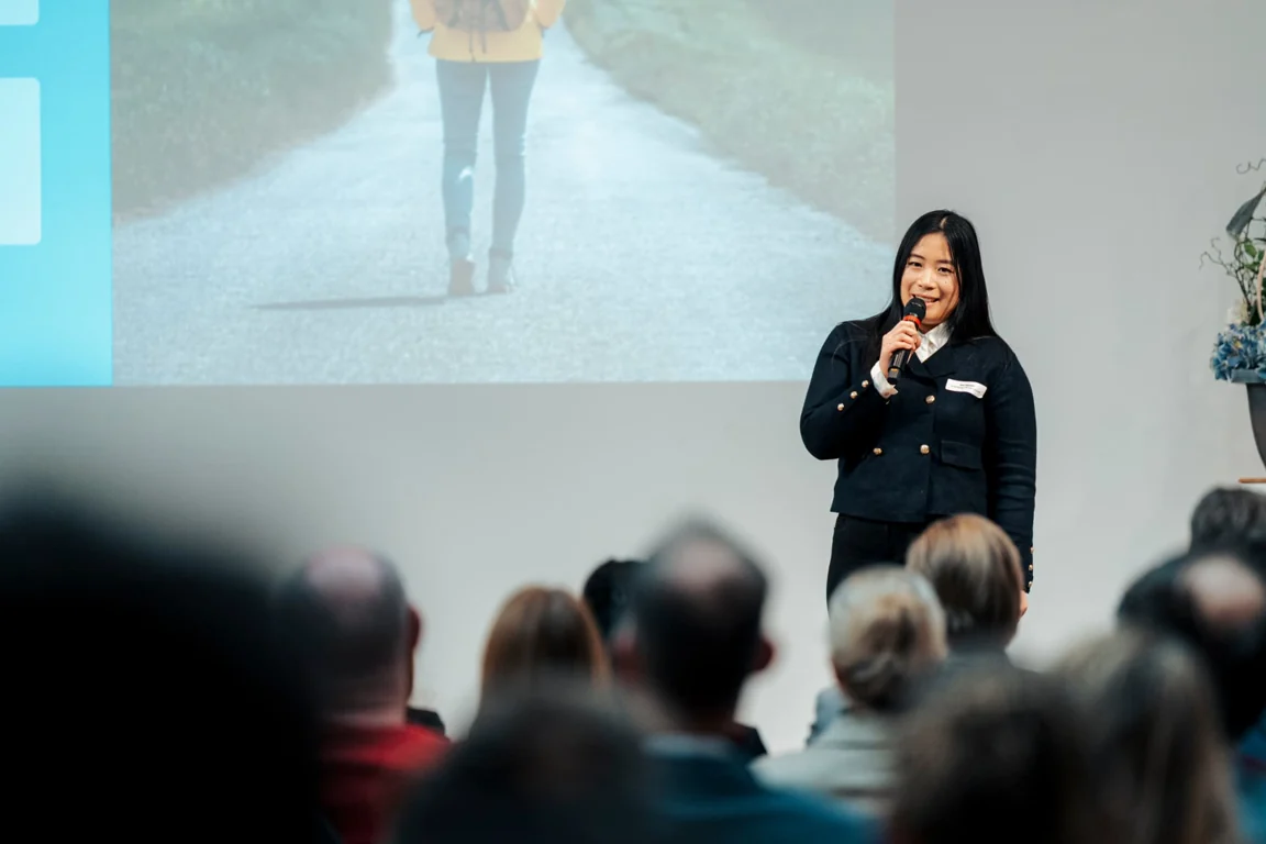 Referentin mit Mikrofon vor Präsentation und Publikum beim KI-Lounge-Kongress am 29. Januar 2026.